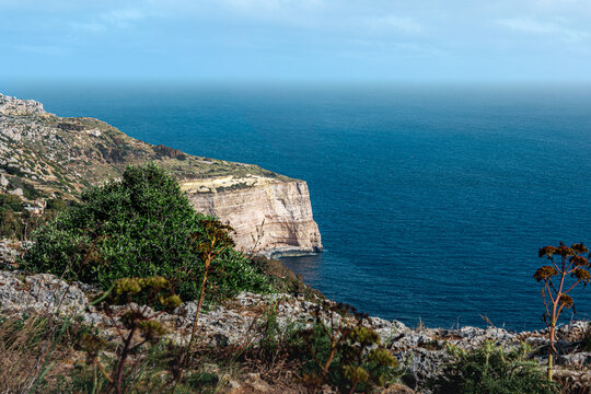 landscape of the dingli cliffs from the coast with limestone cliff face, lush green foliage on summer evening sunset with Mediterranean Sea below on overcast day