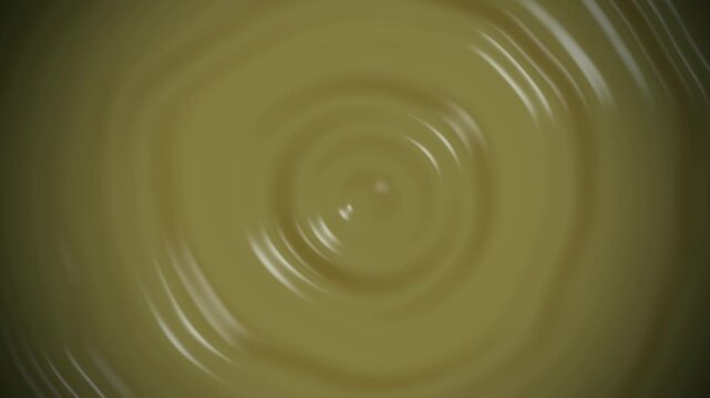 Concentric ripples of creamy mustard yellow liquid pudding or custard swirling in slow motion