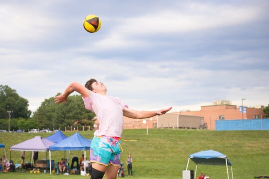 Volleyball player jump serving the ball in a grass doubles tournament