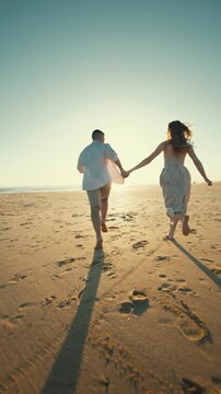 Couple runs on the beach at sunset, enjoying time together near the ocean shore and creating joyful memories