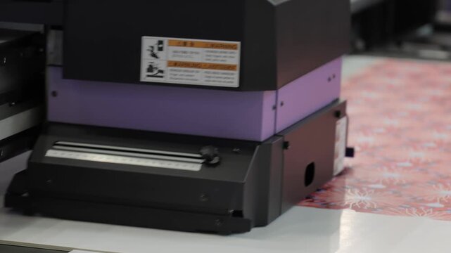 Industrial digital uv printer applying vibrant pattern on fabric material in manufacturing facility.