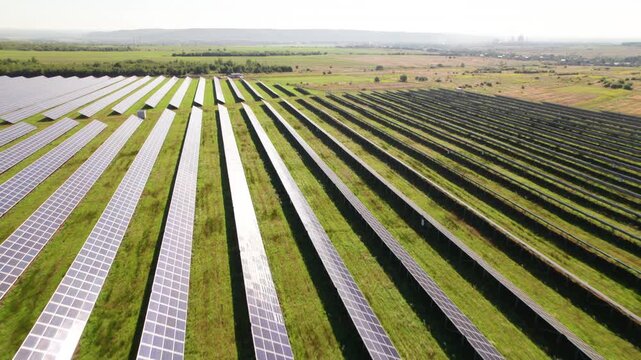Aerial view of solar modules forming structured rows across green land. Great for electricity generation visuals, business presentations, and climate communication