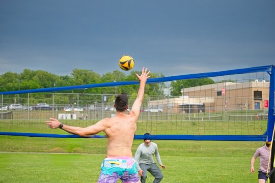 Volleyball doubles player reaches to tap the ball over the net