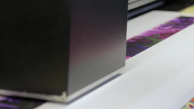 Large format printer creating colorful image on paper, printing machine working close up.