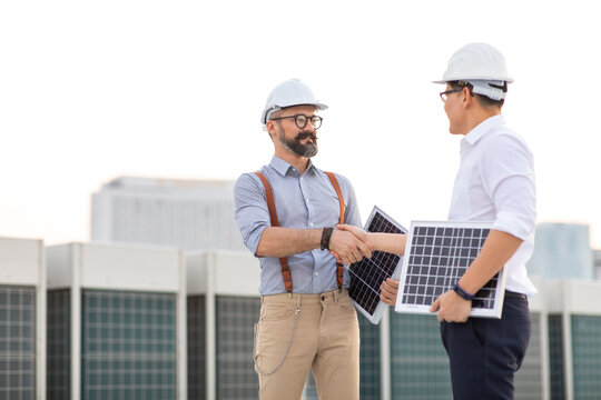 Electrical Engineer Technician and CEO executive business people in hard hat helmet making handshake after meeting. clean and green alternative energy concept.