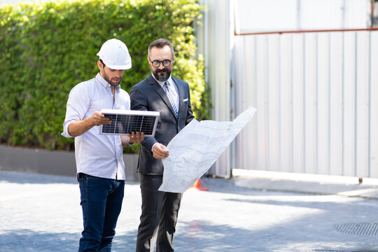 Hipster business man and Office building owner and energy engineer plan a project to build a solar panel for the building under construction. clean and green alternative energy concept.