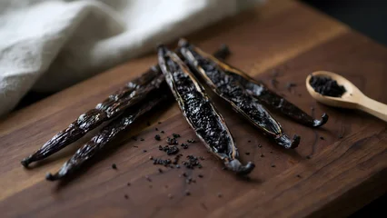 Smoked vanilla beans on wooden cutting board with spoon and black crumbs © Kitta Studio