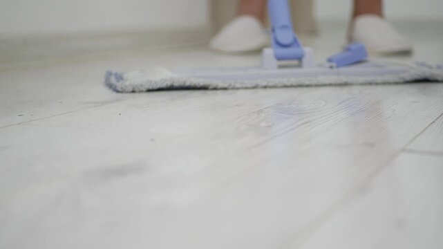 Blurred Shooting with a Person Washing and Cleaning the Wooden Floor from the Room Using a Mop. Mopping the Office Floor with Water and Detergent, Cleaning the Dirt.