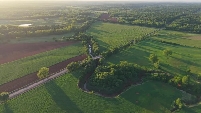 Aerial view of a country road bridge crossing a sharp horseshoe bend creek at sunset, Oklahoma