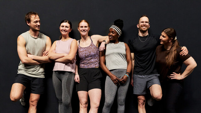 Multicultural group of friends posing after a gym workout, smiling and relaxed together.