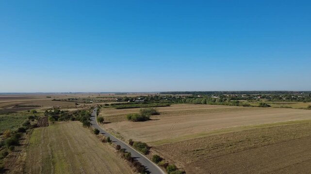 Car Traveling on Asphalt Road Crossing Cultivated Farmland Drone Shot. Drone View Car Driving on Road Through Cultivated Fields.