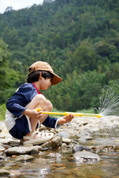 Playful Chinese boy plays in a mountain stream on a summer's day.