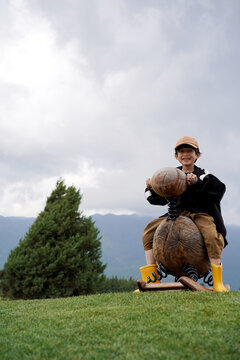Chinese boy rides a wooden horse on a high-altitude meadow