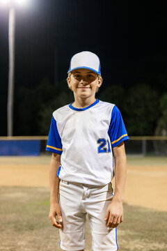 Young Player Stands on Baseball Field at Night