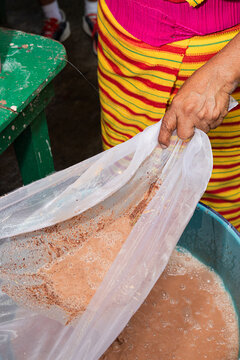Straining cacao drink into a blue mixing bowl
