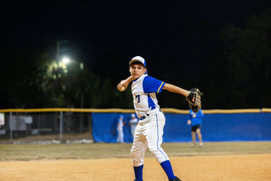 Young Fielder Prepares to Throw Ball at Night Game