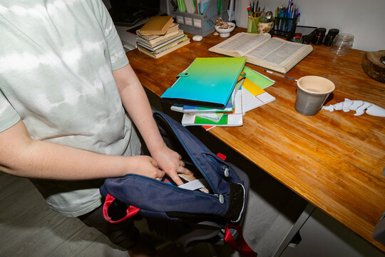Child packs backpack with school supplies