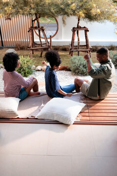 Friends relax on a deck overlooking a modern garden.
