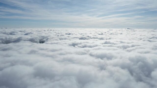 Aerial view of snowy mountain peaks and valleys under cloudy sky.
