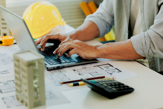 Innovative corporate manager analyzing structural math and building model scales on dual screens.