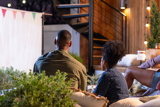 Family enjoys outdoor movie night with projector and snacks.