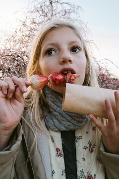 A girl eating sugar glazed strawberries