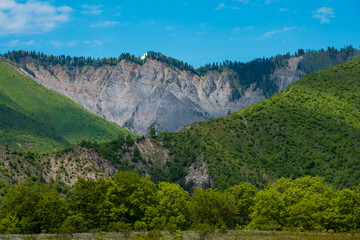 Fototapeta premium Green mountain valley with rugged cliffs and clear blue sky