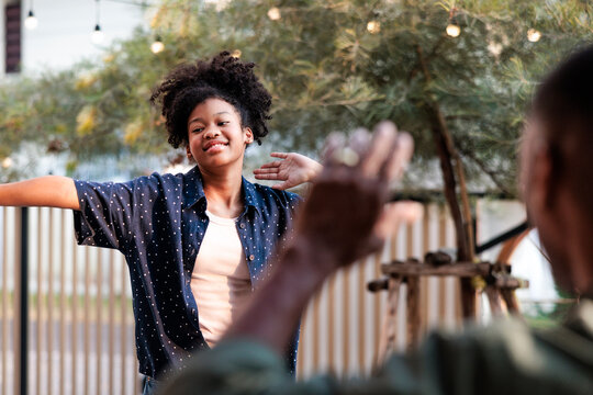 Girl playfully dancing while parent gestures in backyard