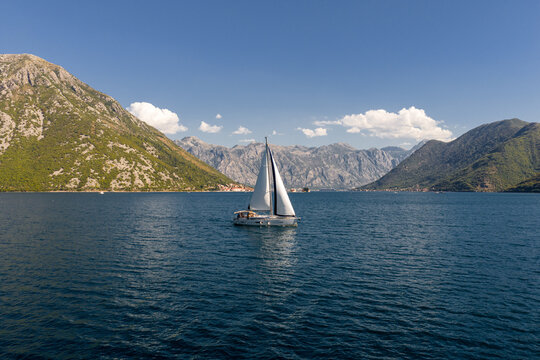 yacht with white sails and mountain fjord bay of Kotor