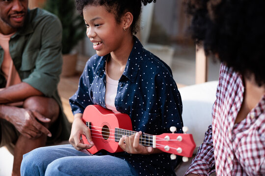 Girl plays ukulele for family.