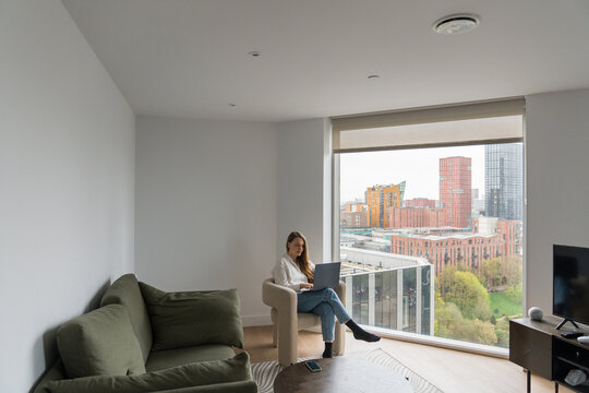 Woman Using Laptop in Apartment With City View