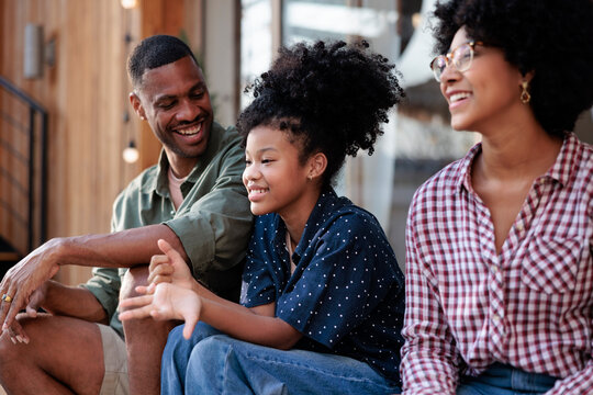 Happy family sitting together, smiling and talking outdoors.