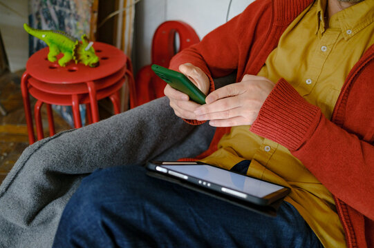 Close-up of designer hands holding smartphone over graphic tablet
