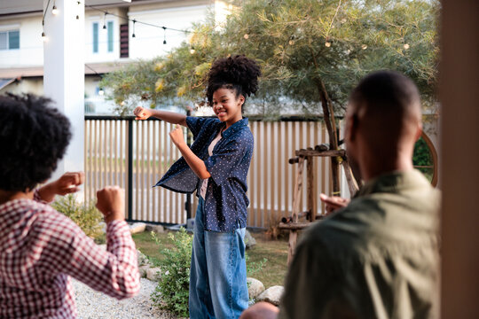Girl dancing while mother joins in and father watches in backyard