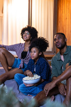 Family watching a movie with popcorn on an outdoor patio.