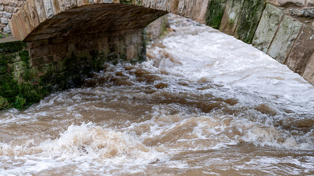 Rainswollen river beneath stone arch bri 2