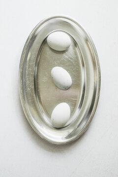 Three White Eggs on a Clear Tray on a White Surface