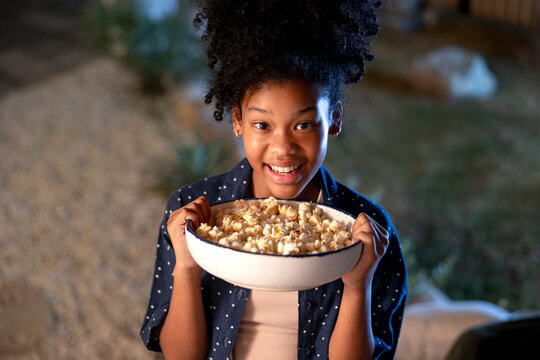 Smiling girl holds a bowl of popcorn.