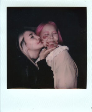 Pink-haired friend plants a kiss on her companion's cheek