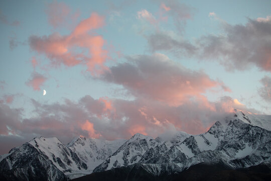 Crescent Moon Over Snowy Mountains at Sunset