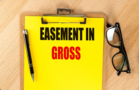 Easement in gross concept with clipboard, pen and eyeglasses on wooden desk, representing property rights, land use agreement