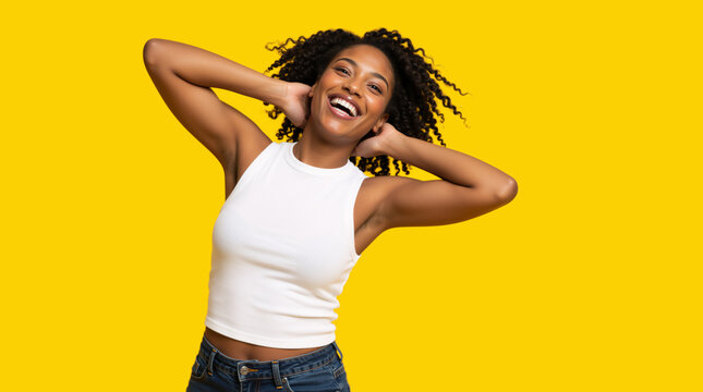 Joyful young Black woman with curly hair laughing on yellow background. Cheerful female model in white tank top expressing happiness and positive energy