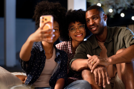 Daughter taking selfie with parents on cozy outdoor evening