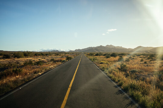 Open desert road at sunset leading into mountains 