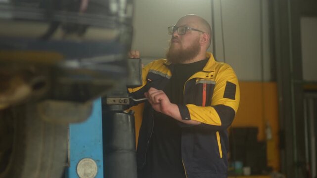 Caucasian male mechanic with glasses and a beard works alongside a female technician, reviewing a digital tablet and giving a thumbs-up. This high-energy commercial imagery represents gender diversity