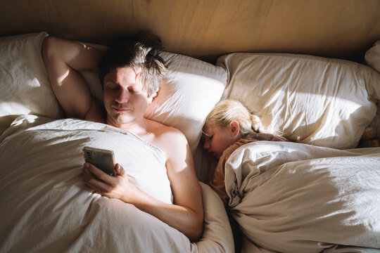 A man with a mobile phone in bed in the morning