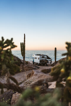 Remote camper van by ocean seen through desert foreground