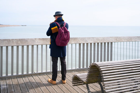 Traveler looking at sea from coastal pier
