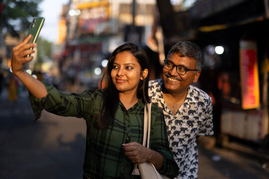 A middle aged man with his daughter taking selfie at outdoors