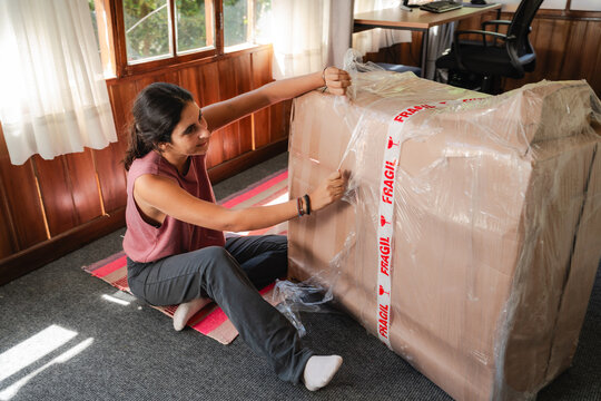 young Woman Unpacking Large Fragile Box at Home